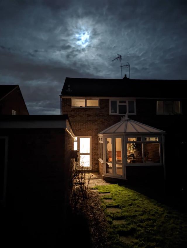 Semi-detached house lit from inside, dramatic lighting from moon
